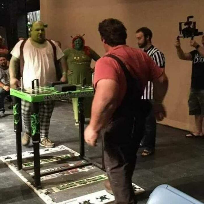Two men in costume face off in a bizarre arm wrestling contest featured in cursed pics and memes on Instagram.