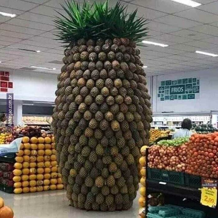 Giant pineapple structure made of many pineapples stacked in a grocery store showcasing cursed pics and memes theme.