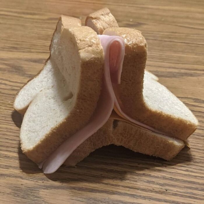 Unusually constructed sandwich with multiple slices of bread and ham, showcasing a cursed photo from an Instagram page.