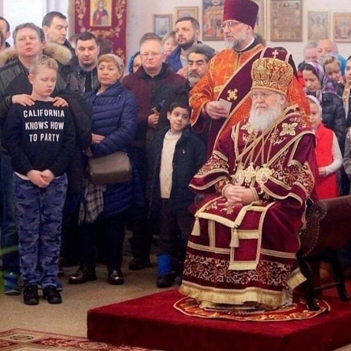 Boy wearing a shirt that says California knows how to party at a religious ceremony with a group in an unusual cursed photo.