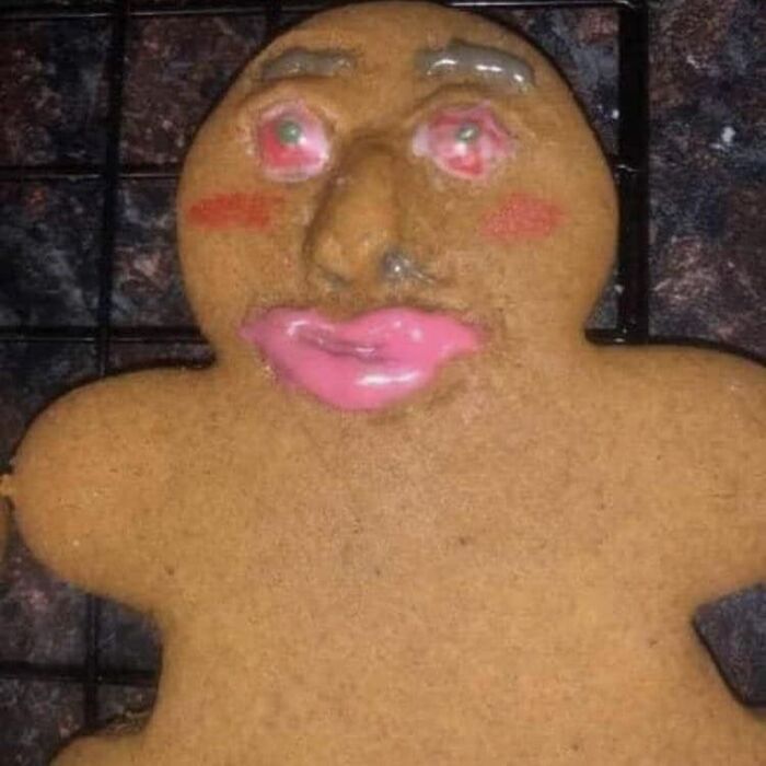 Gingerbread cookie with distorted facial features and bright pink icing lips, part of cursed pics and memes collection.