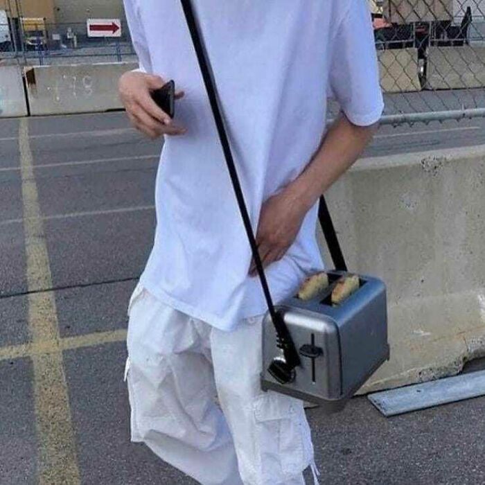 Person wearing all white carrying a toaster bag with bread slices, a cursed pic from a popular Instagram page of memes.