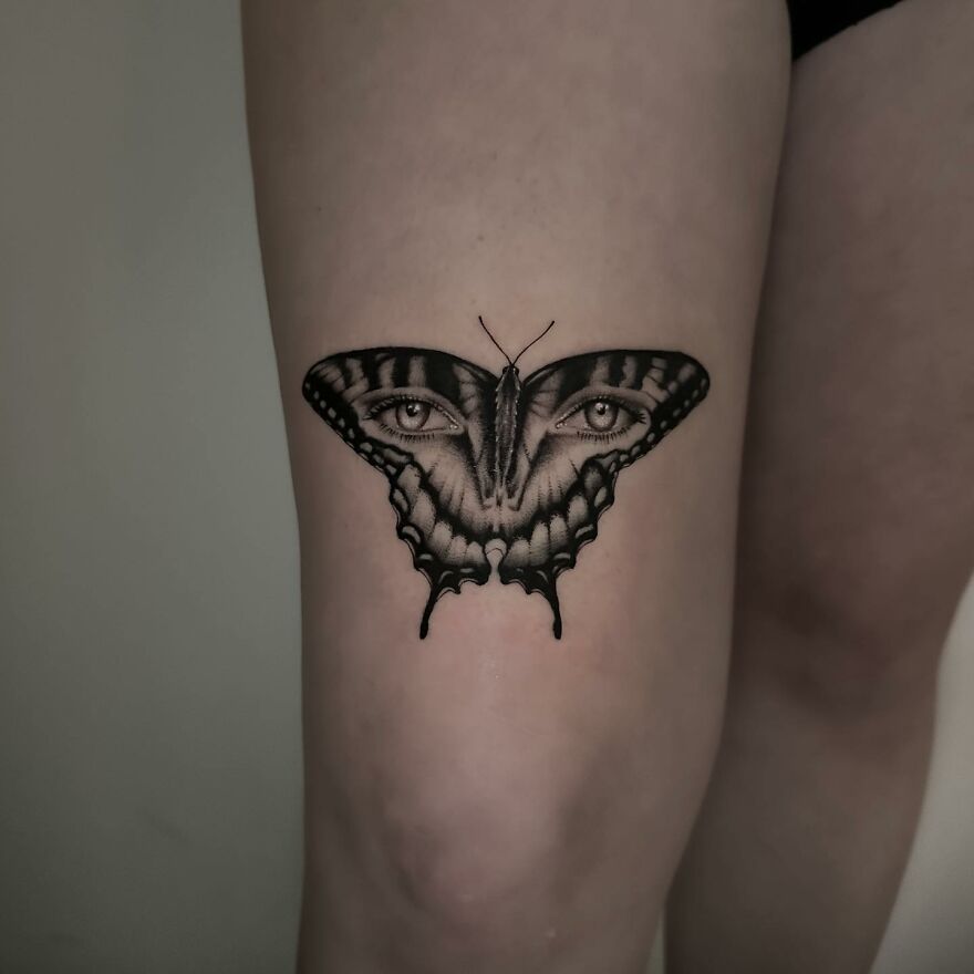 Tattoo of a butterfly with realistic eyes, created using a single needle on a person's skin.
