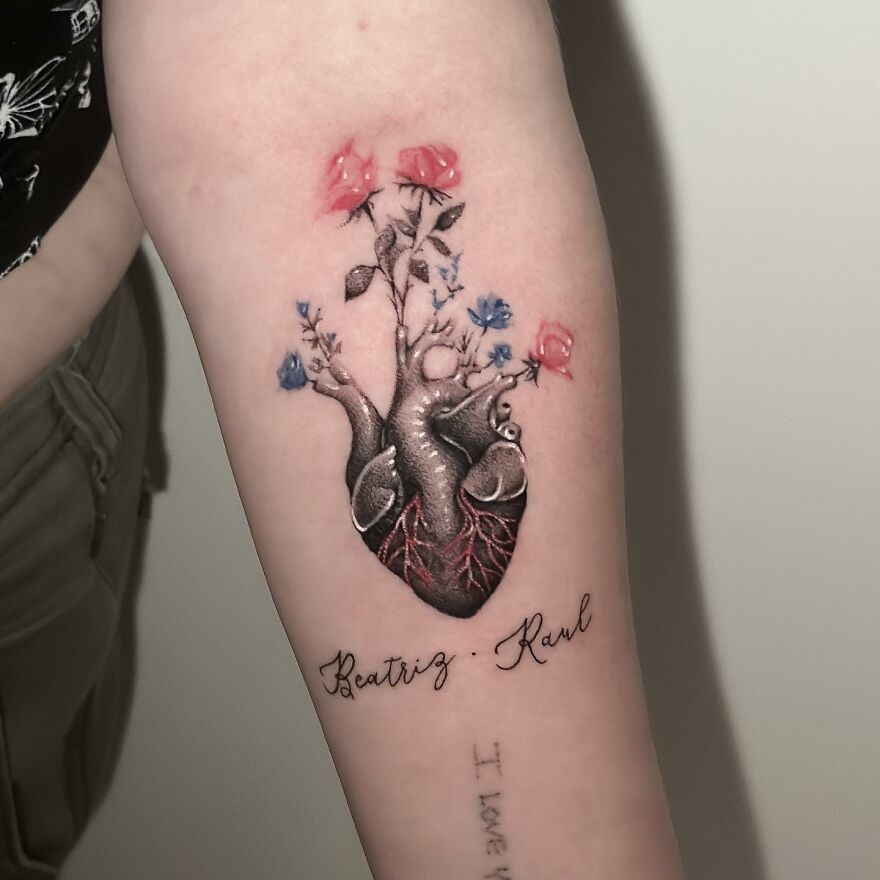Single needle tattoo with anatomical heart and flowers on arm.
