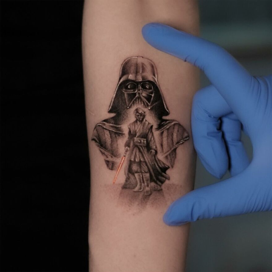Single needle tattoo of Star Wars characters, including Darth Vader and lightsaber, on an arm with a gloved hand nearby.
