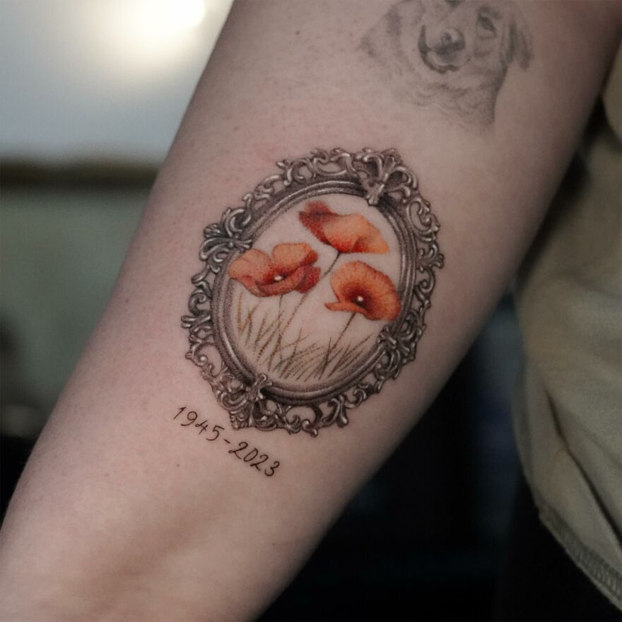 Single needle tattoo of poppies framed by ornate border on arm with dates 1945-2023.