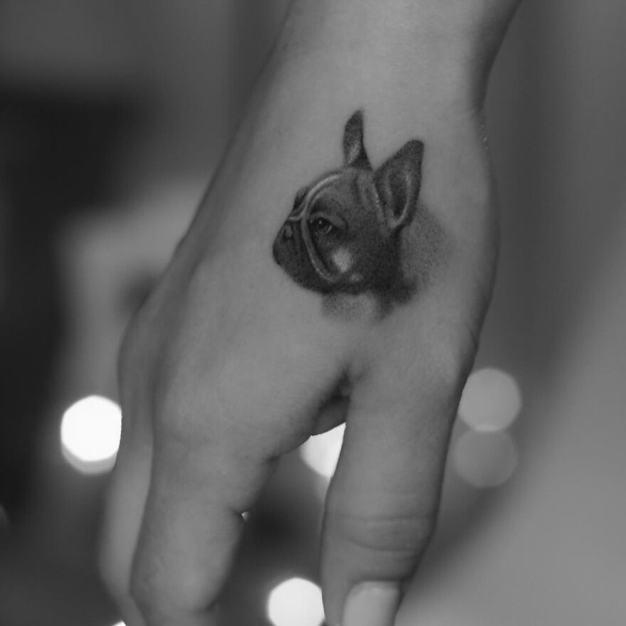 Single needle tattoo on hand featuring a detailed image of a dog’s head in black and gray.