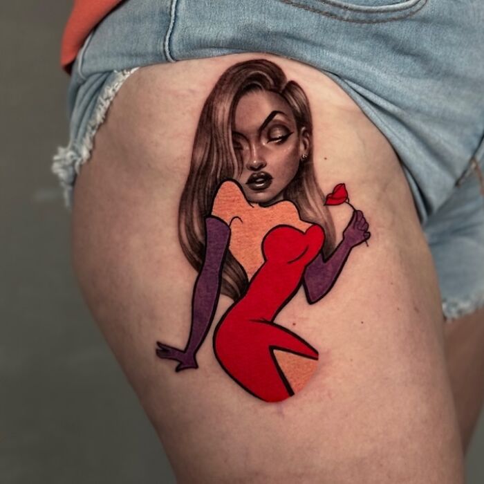 Tattoo merging two artistic styles, featuring a stylish woman in red and orange, showcased on a person's thigh.