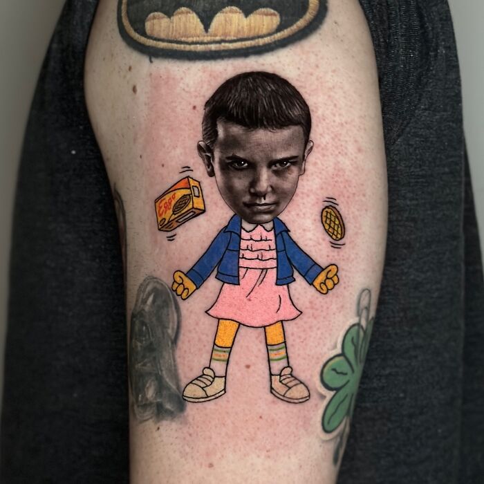 Tattoo combining two artistic styles, featuring a character with a serious expression, waffles, and box design.