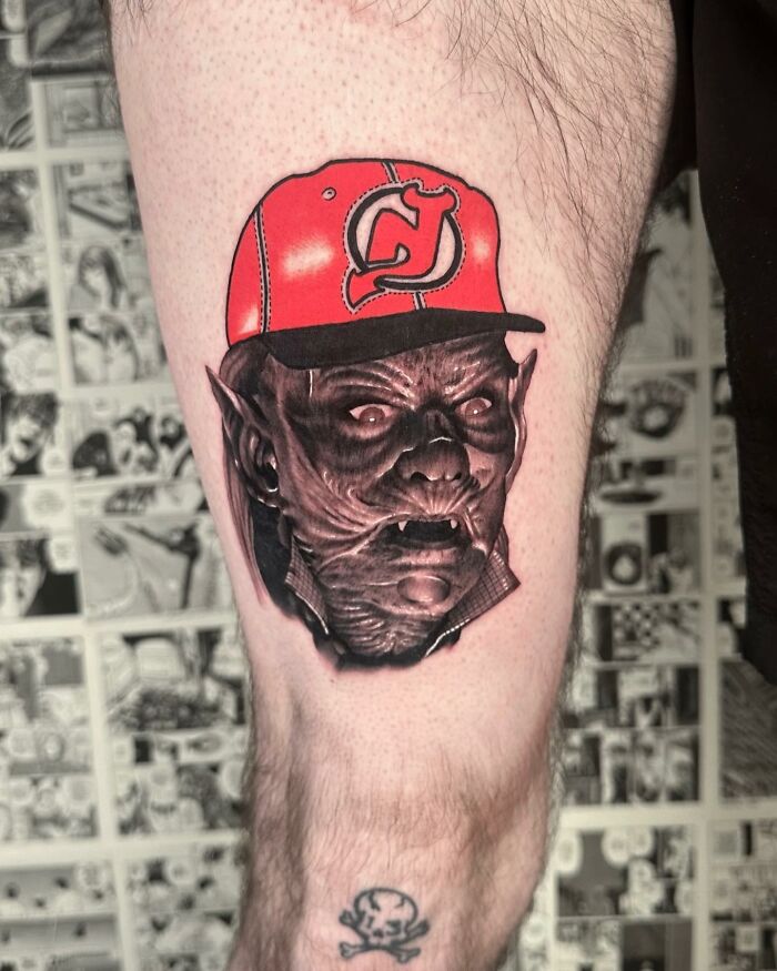 Tattoo blending styles: a creature with a red cap on a person's leg, comic strip background.