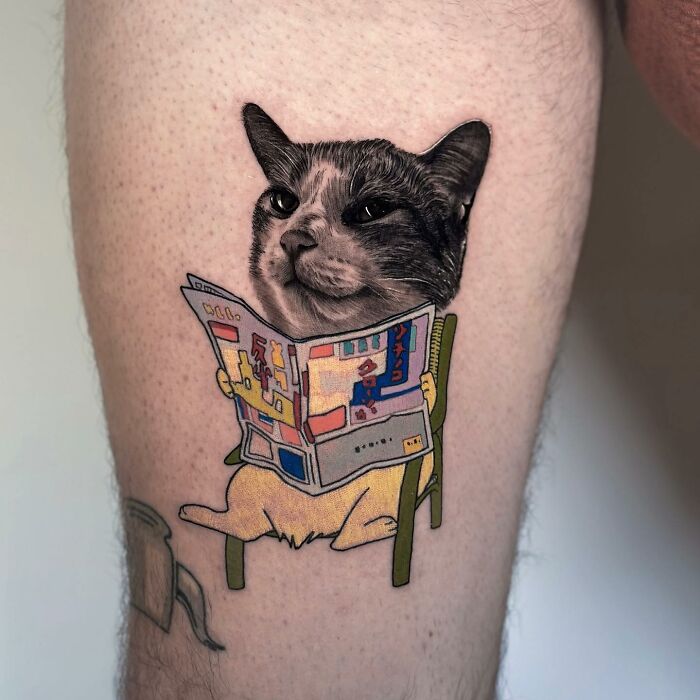 Tattoo of a cat reading a newspaper, merging two artistic styles seamlessly on a person's leg.