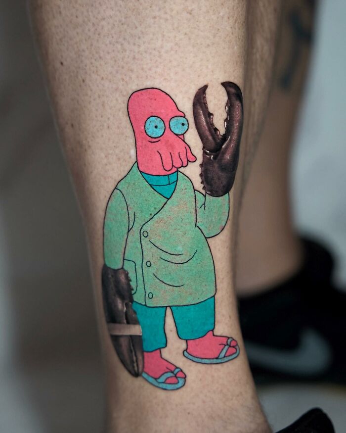Tattoo featuring a colorful cartoon character with lobster claws, merging two artistic styles seamlessly.