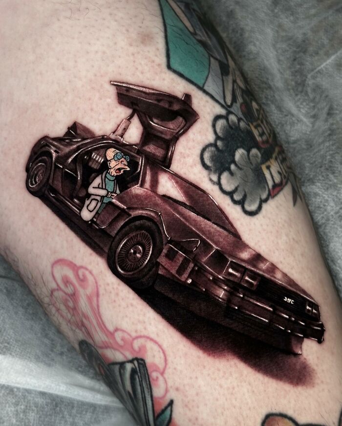 Tattoo of a cartoon character in a futuristic car, blending two artistic styles seamlessly, on forearm by Mat Rule.