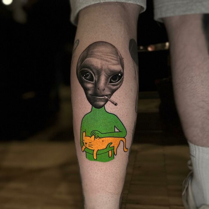 Tattoo featuring a surreal combination of an alien with a cigarette and a green figure holding an orange cat.