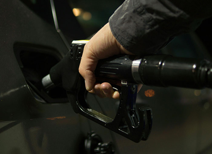 Person holding gas pump nozzle fueling a vehicle at night, highlighting things people just discovered today.