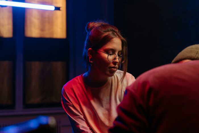 Tattoo artist concentrating deeply in a dimly lit studio setting.