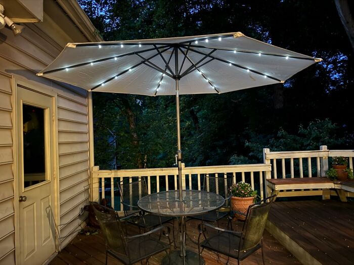 Backyard patio setup with illuminated umbrella, table, and chairs, ideal for July 4th parties and outdoor gatherings.
