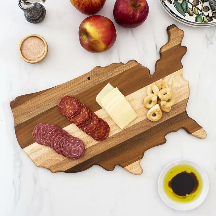 Wooden USA-shaped charcuterie board with meats, cheese, and snacks, perfect for backyard July 4th party essentials.