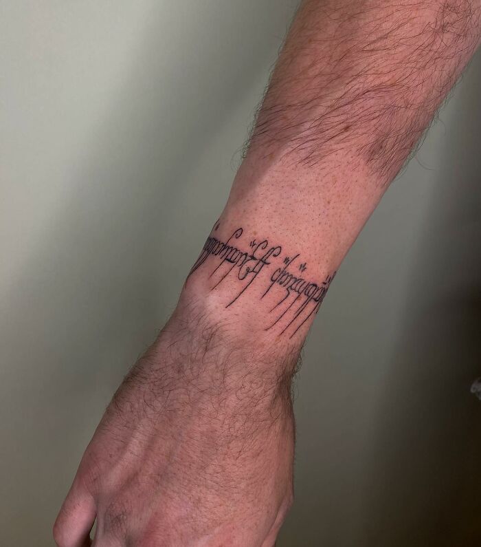 Tattoo on wrist with intricate lettering, showcasing a design that artists found uncomfortable to create.