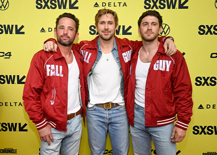 Ryan Gosling at SXSW event, wearing a red jacket and jeans, posing with two men, showcasing style changes.