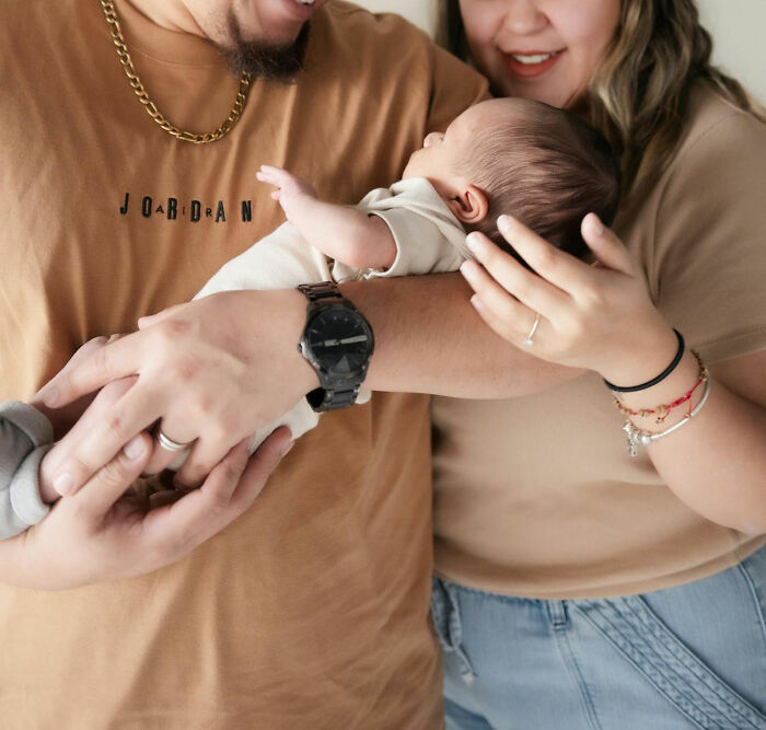 A family holding a newborn, showcasing the pinnacle of dad humor and warmth in a home setting.