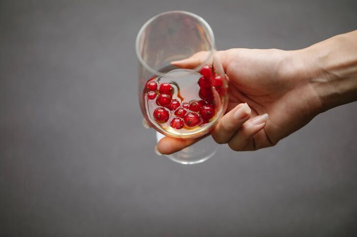 Hand holding a glass with red currants and a small amount of liquid, symbolizing people in their 40s, 50s, and 60s.