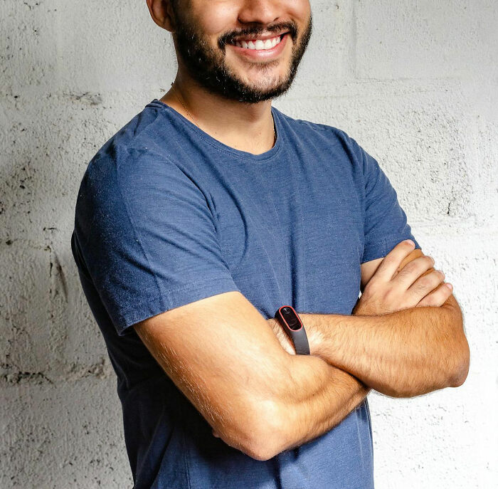 Smiling man in a blue shirt with arms crossed, embodying dad humor charm.