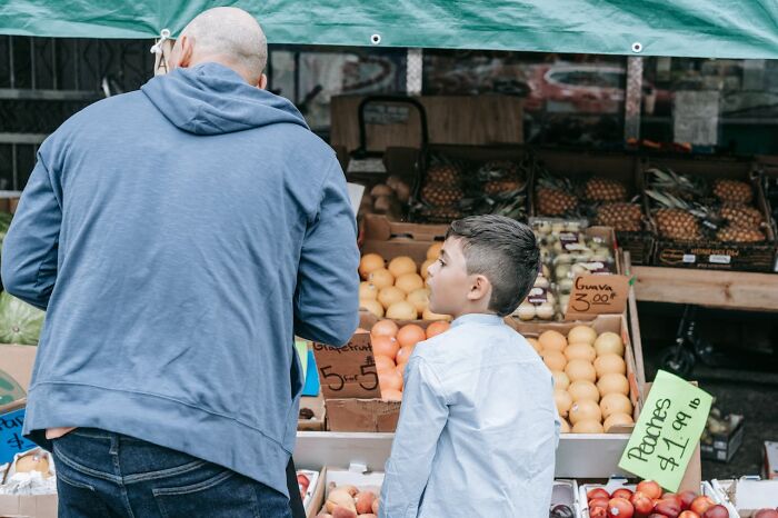 Man and boy shopping for fruit at a market stall with peaches and guava, illustrating frightening vacation stories.