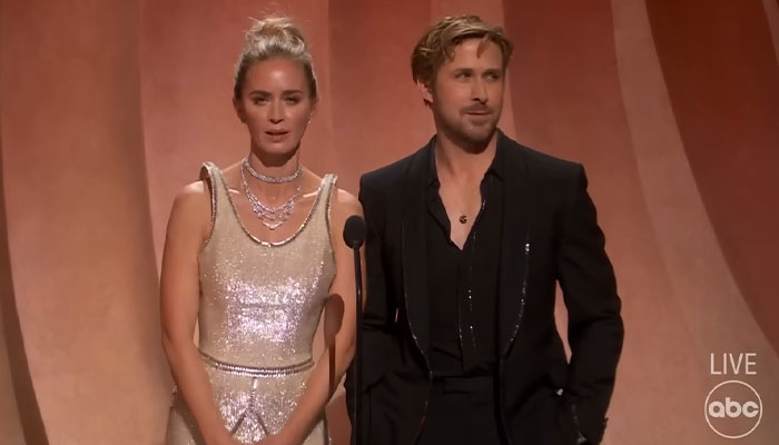 Man and woman on stage in formal attire, with man wearing a black suit, relevant to Ryan Gosling pictures.
