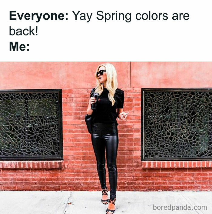 Woman in black outfit holding drink, standing by brick wall. Caption humorously contrasts spring colors with her attire.
