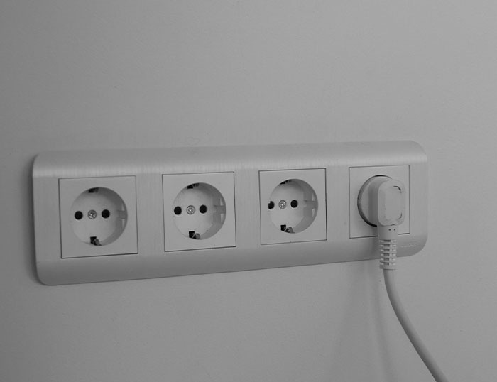 Power outlet strip mounted on wall with one plug inserted, illustrating unusual house rules about guest behavior and home control.