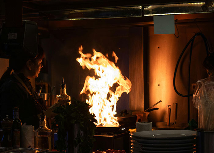 Person cooking with large flame in kitchen, illustrating everyday things most people don’t realize are deadly fire risks