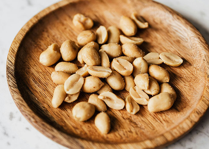Salted peanuts on a wooden plate, illustrating one of the everyday things most people don’t realize are deadly.