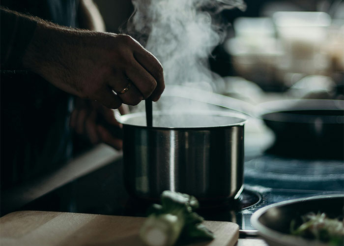 Hand stirring steaming pot on stove, highlighting everyday things most people don’t realize are deadly risks.