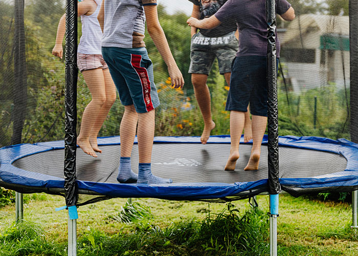 Children jumping on a trampoline outdoors, illustrating everyday activities that can be unexpectedly deadly risks.