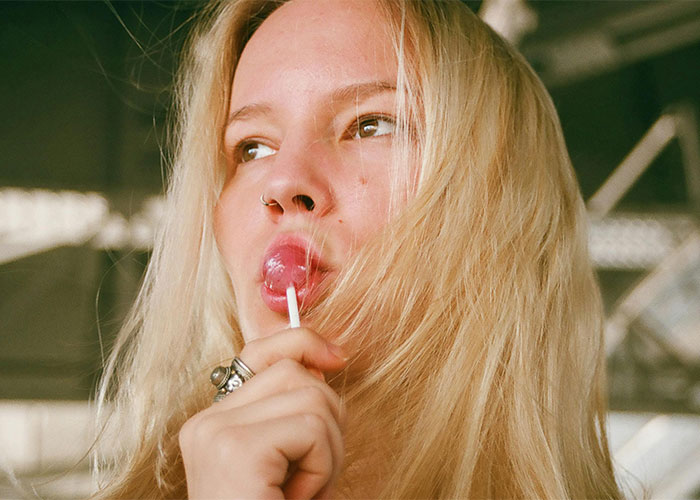 Young woman with blonde hair sucking on a lollipop, highlighting everyday things most people don’t realize are deadly.