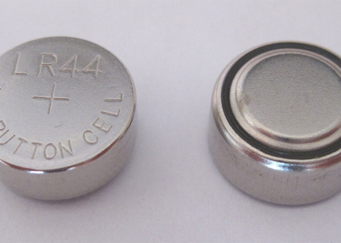 Two small LR44 button cell batteries on a white surface illustrating deadly everyday items risk.