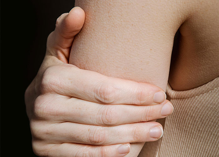 Close-up of a person holding their arm, illustrating the risks of everyday things considered deadly.