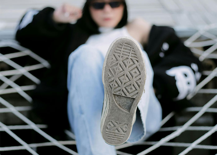 Person wearing sunglasses and showing sole of shoe while reclining on a hammock, illustrating everyday things deadly risks.