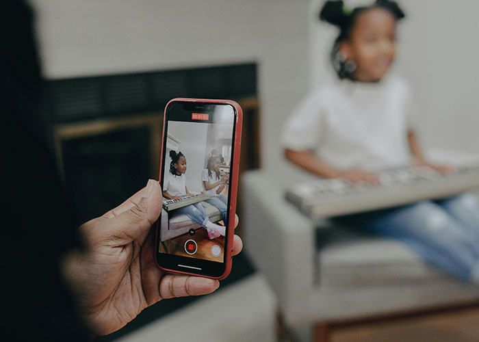 Parent recording child playing keyboard at home, highlighting moments that some might see as signs of being a bad parent.
