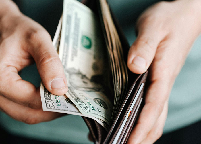 Hands holding a wallet with cash being pulled out, illustrating financial struggles tied to bad parent concerns.