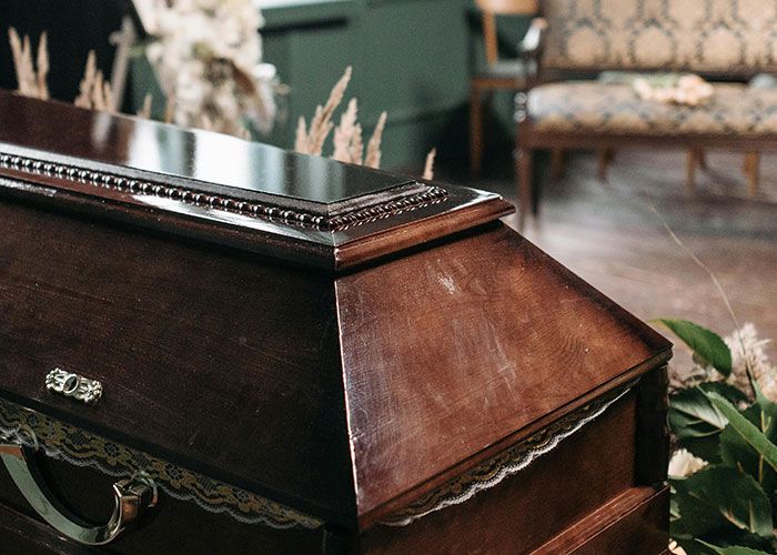 Wooden coffin in a dimly lit room with flowers nearby, illustrating themes around what screams bad parent behavior.