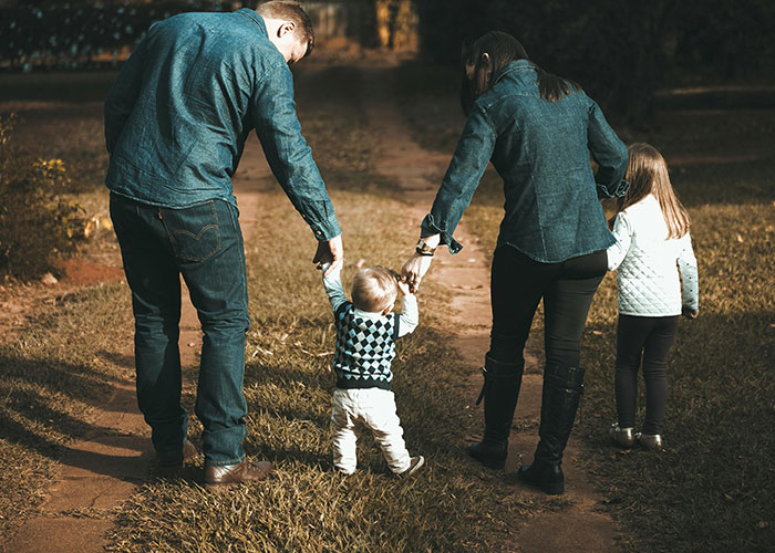 Family walking outdoors with two children, highlighting common signs that scream bad parent behavior.