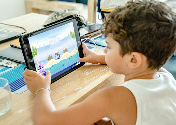Young child playing a video game on tablet indoors, illustrating common signs of bad parenting and screen time habits.