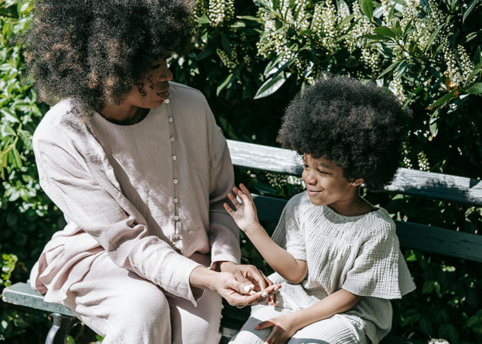 Mother and child with matching hairstyles sitting on a bench outdoors, illustrating insights on bad parenting perceptions.