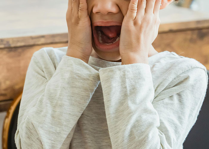 Child covering face and screaming in frustration, illustrating moments that scream bad parent experiences.