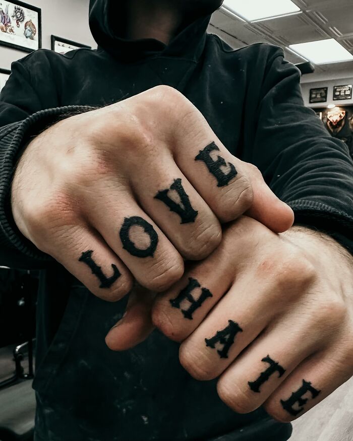 Knuckle tattoos reading "LOVE" and "HATE" in a tattoo studio setting.