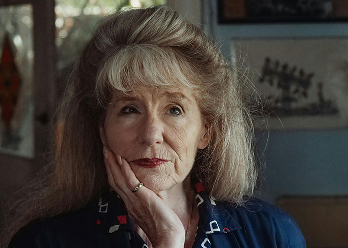 Older woman reflecting thoughtfully at home, representing traditional wives sharing real experiences from the 20th century.