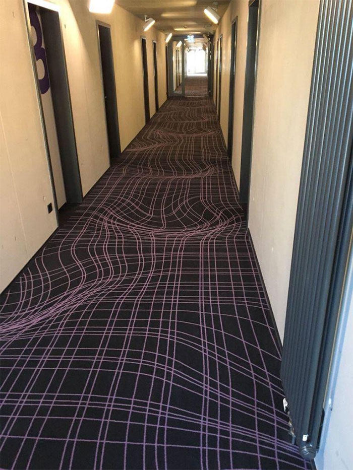 Hallway with distorted carpet pattern creating an optical illusion, showcasing awful interior design choices.