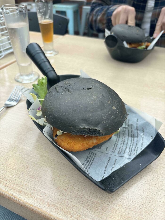 Black bun fish sandwich served on a frying pan, showcasing one of the most ridiculous ways food was served in restaurants.